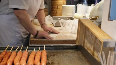 Chef rolls soft dough on wooden board in busy asian street food stall Stock Footage 337175714