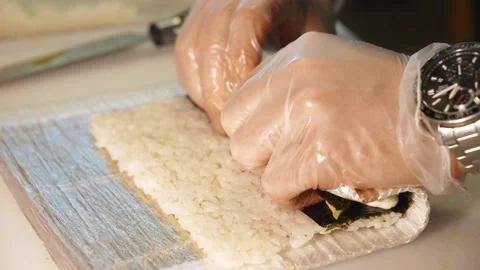 Chef rolls sushi with avocado and cream cheese using a bamboo mat 스톡 동영상 346715125