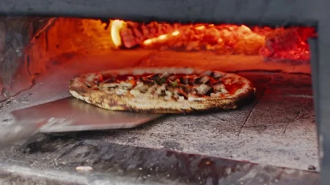 Chef Rotates a Pizza Using a Peel in an Outdoor Wood-Fired Oven Stockbeeldmateriaal 204923874