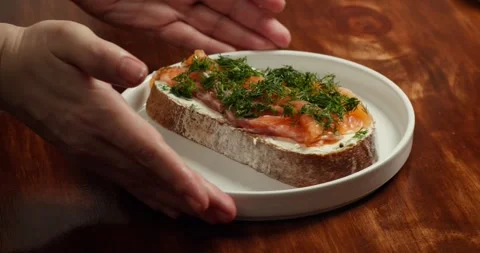 The chef rotation the plate in camera on which lies a salmon sandwich sprinkled Vidéo 327145735