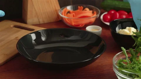 Chef in rubber gloves put fresh arugula  leaves in to black plate Stock Footage 103845861