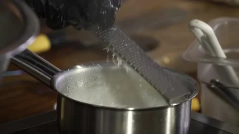 Chef rubs cheese on a grater in boiling sauce Stock Footage 148315411
