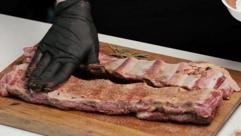 Chef rubs spices on beef or pork ribs before grilling Stock Footage 247788997