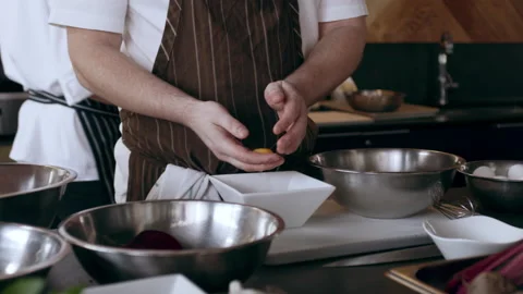 Chef running egg yolk in hand to separate the egg yolk and egg white into a bowl Stock Footage 199463669