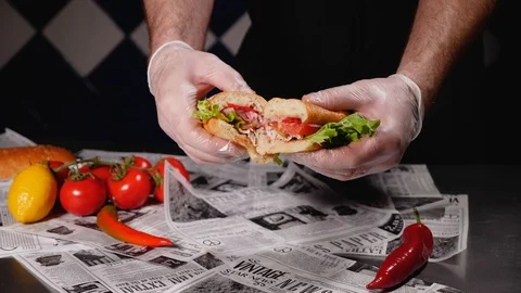 A chef in safe gloves shows a half-cut freshly prepared mackerel burger Close up Stock Footage 128293063