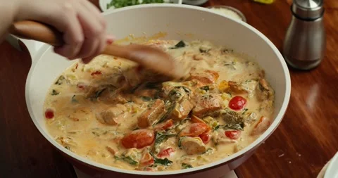 Chef sauteed tomatoes with spinach and creamy sauce, adds seared salmon, and Stock Footage 318572560