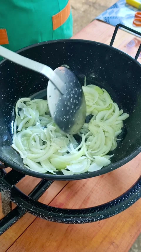Chef sauteing sliced white onions in a paella pan Stock-Footage 343677952