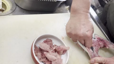 Chef scraping tuna meat from the tail bone onto a plate of minced tuna Video stock 338166784