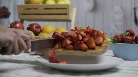 Chef scrapping cut up strawberries onto plate near other fruit - closeup shot Stock Footage 341026537