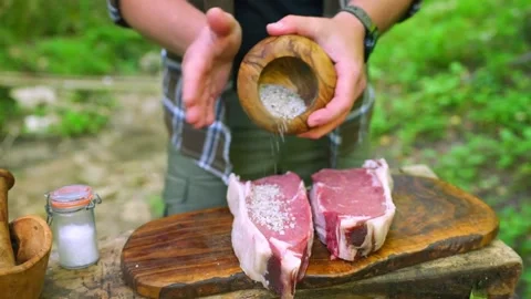 Chef seasoning raw beef steaks with sea salt outdoors Stock Footage 336656790