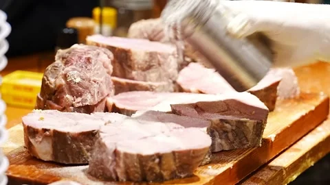 Chef seasoning thick roasted meat portions with salt on wooden board Stock Footage 345930332