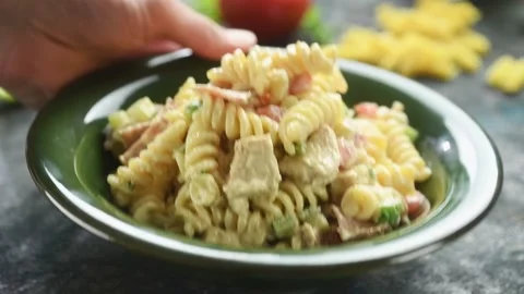 The chef serves freshly prepared chicken pasta salad  on the table. Stock Footage 198533785