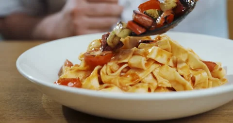 Chef serves his pasta putting vegetables, mixing it with spaghetti, cooking Stock-Footage 133240988