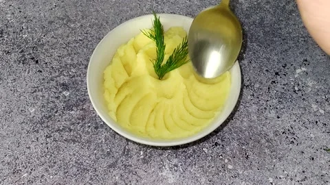 The chef serves mashed potatoes in a bowl with a spoon Stock Footage 230015426