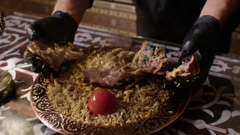 Chef Serves Slow-Cooked Meat and Spiced Rice on Ornate Plate in Traditional Stock Footage 345953050
