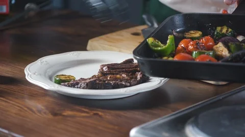 Chef serves vegetables a grilled steak dish in a restaurant. Vidéo 124712797