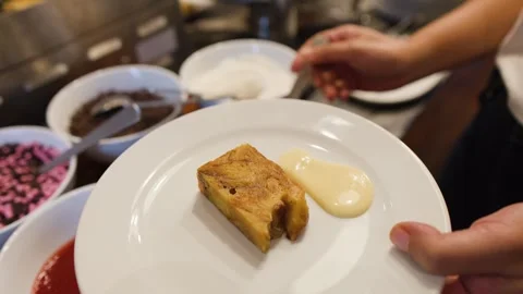 Chef Serving Bread Pudding with Custard Sauce at a Buffet Dessert Station Stock Footage 336353479