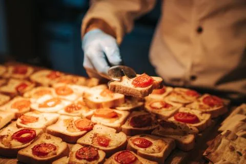 Chef is serving canapes toasted bread with cheese and tomato in a restaurant. Stock Photos