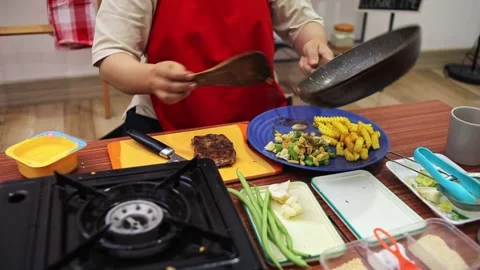 Chef serving cooked side vegetables onto plate during steak dinner preparation Stock Footage 345379951