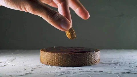 Chef serving a dark chocolate tart putting an almond on it Stock Footage 127643897