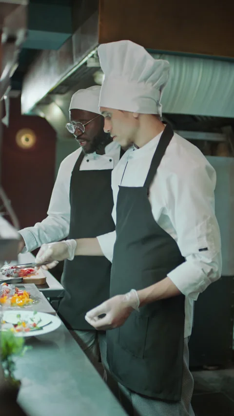 Chef Serving Food on Plate and Teaching Apprentice in Kitchen of Restaurant Stock-Footage 273451675