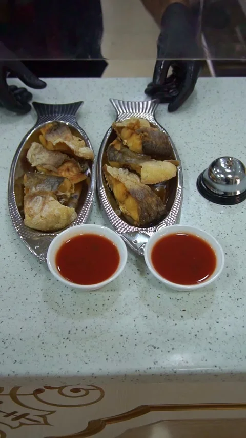 Chef serving fried fish dishes on fish-shaped plates with tomato sauce bowls at  Stock Footage 342345257