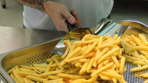 Chef serving golden and crisp potato french fries on a basket with a napkin Stock Footage 127715844
