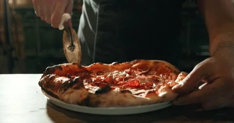 Chef serving meat pizza on plate, using pizza cutter Видео 201468007
