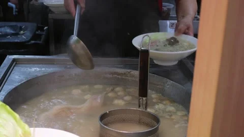 Chef serving noodle soup with dumplings from large pot at street food stall Stock Footage 336442185