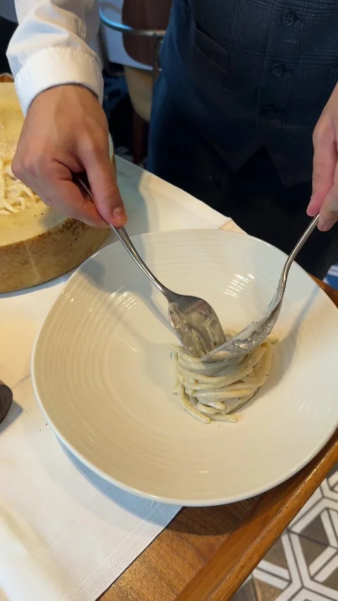 Chef serving pasta from cheese wheel into plate in restaurant Stock Footage 340581385
