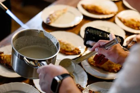 Chef serving sauce over plated omelets on wooden table Stock Photos