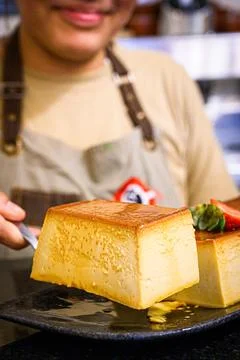 Chef serving slice of homemade flan with strawberries Stock Photos