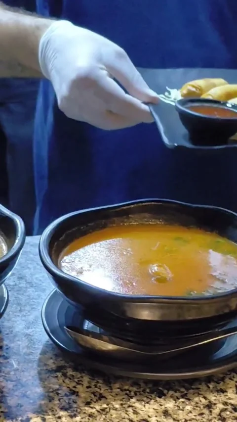 Chef serving spicy Tom Yum soup and fried spring rolls on counter Stock Footage 346850058