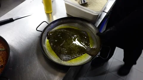 Chef shaking a pan cooking a large turbot fish in sauce Video stock 330991980