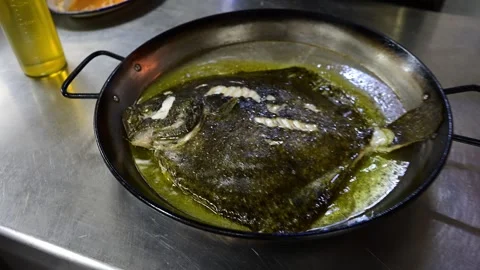 Chef shaking a pan cooking a large turbot fish in sauce Video stock 330991981
