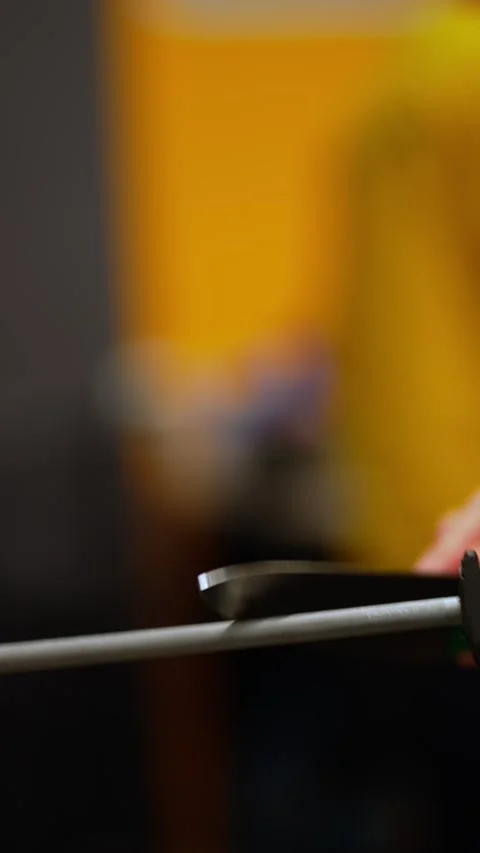 Chef Sharpening Knife in Kitchen. Blurred chef sharpening knife against vibrant Stock Footage 267604731