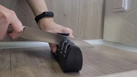 Chef sharpens a knife with a sharpener Stock Footage 231696683