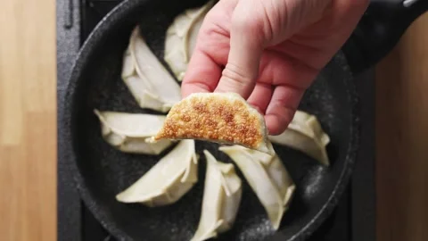 Chef shows crisp golden bottom of fried gyoza. Stock Footage 342316224