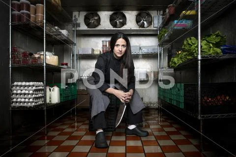 Chef Sitting In Walk-In Refrigerator In Restaurant