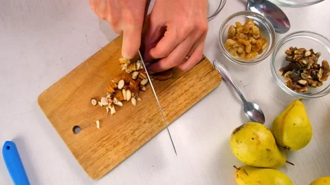 Chef skillfully chopping almonds on rustic wooden board cooking dessert. Stock Footage 312995484