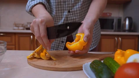 Chef skillfully cuts yellow peppers into strips on wooden surface 库存影片 329062387
