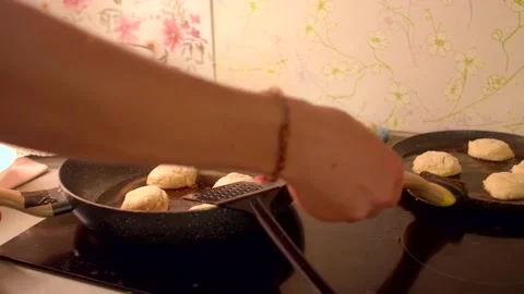 Chef skillfully flips and arranges golden patties on stovetop surface Stock Footage 321028244
