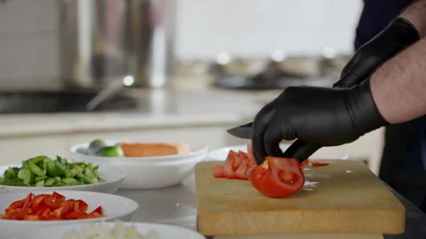 Chef skillfully prepares fresh ingredients in a bustling kitchen, slicing Stock Footage 313113654