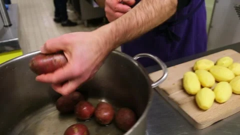 Chef skillfully prepares potatoes for cooking in a professional kitchen setti Stock Footage 307348714