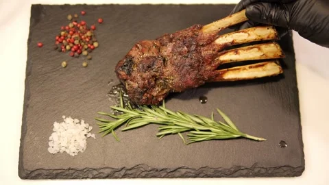 Chef skillfully presents sizzling barbecued ribs on plate, displaying succulent Stock Footage 271658387