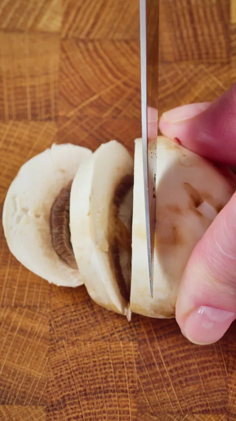 Chef skillfully slices mushroom caps on wooden board Stock Footage 329276822