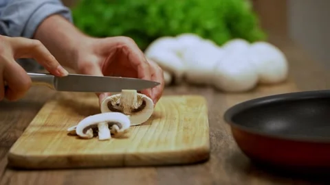Chef skillfully slicing fresh champignon mushrooms on wooden cutting board. Video stock 300311912