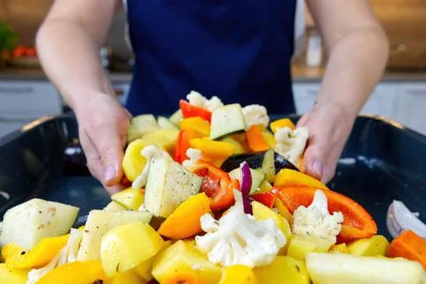 The chef sliced vegetables into a baking tray. the process of making oven Stock Photos