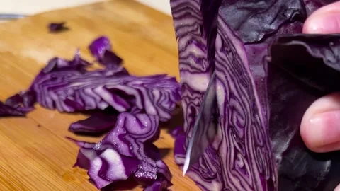 Chef slices and shreds red cabbage with knife on cutting board for soup, salad Stock Footage 345601626