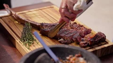 Chef Slices Cuts Large Bone-in Ribeye Tomahawk Steak On Fire Grill Stock Footage 288038779